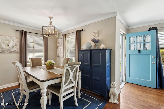 dining space featuring crown molding, a notable chandelier, wood finished floors, and baseboards