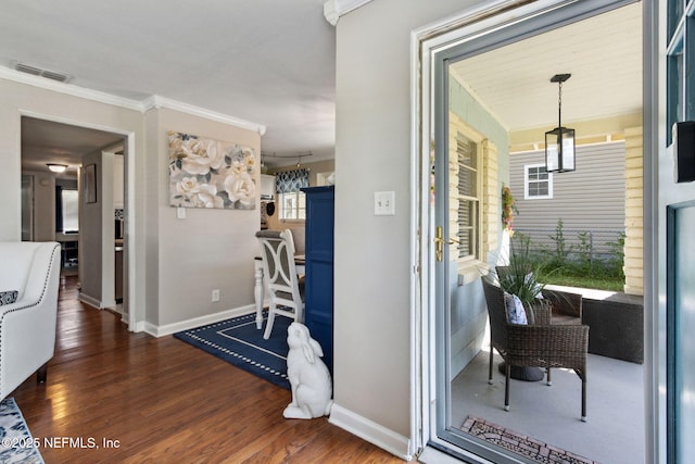 hallway featuring wood finished floors, visible vents, ornamental molding, and baseboards