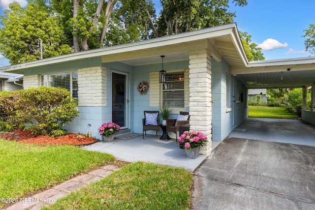ranch-style home with a porch, a front lawn, concrete driveway, and an attached carport