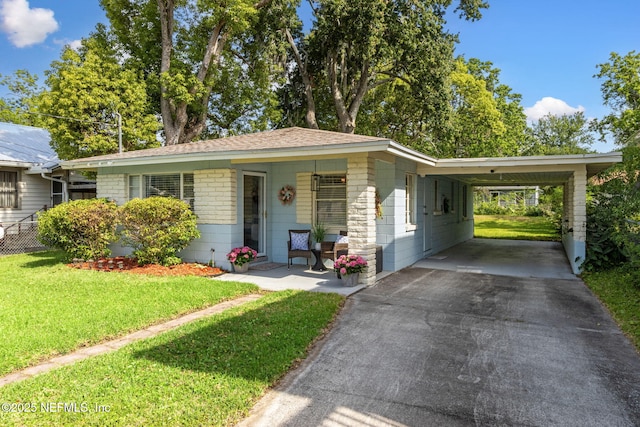 ranch-style house featuring a carport, aphalt driveway, a shingled roof, covered porch, and a front yard