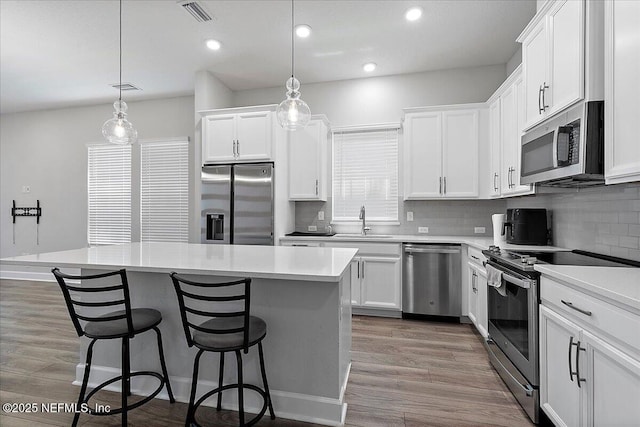 kitchen with decorative backsplash, a breakfast bar area, visible vents, a sink, and stainless steel appliances