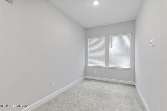 spare room featuring baseboards and light carpet