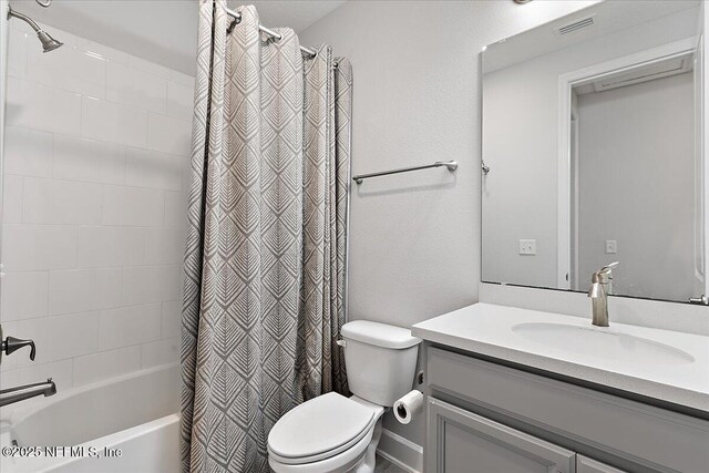 bathroom with vanity, shower / bathtub combination with curtain, and toilet