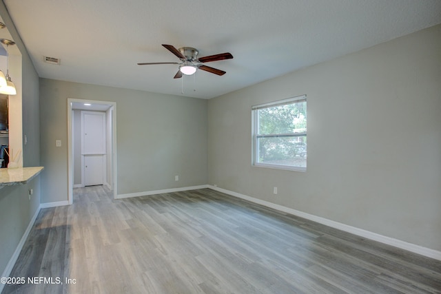 interior space featuring a ceiling fan, visible vents, wood finished floors, and baseboards