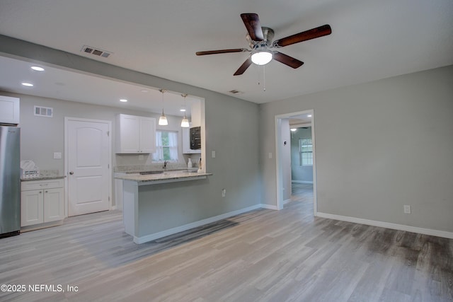 kitchen with visible vents, light wood-style flooring, and white cabinetry