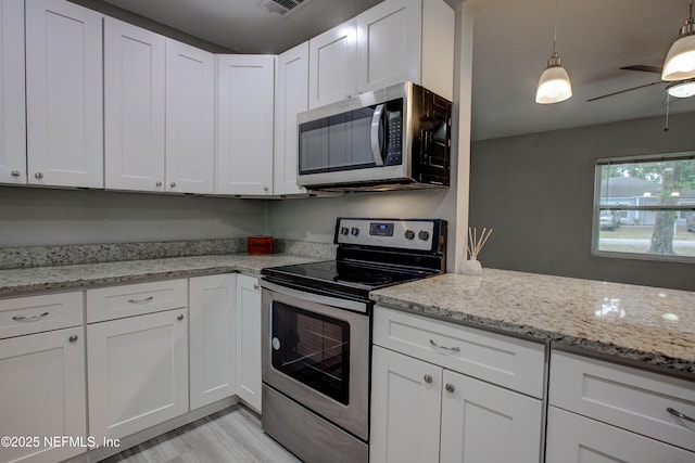 kitchen featuring appliances with stainless steel finishes, white cabinetry, light stone counters, and light wood finished floors