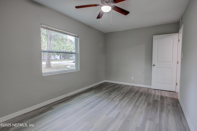 unfurnished room with ceiling fan, wood finished floors, and baseboards