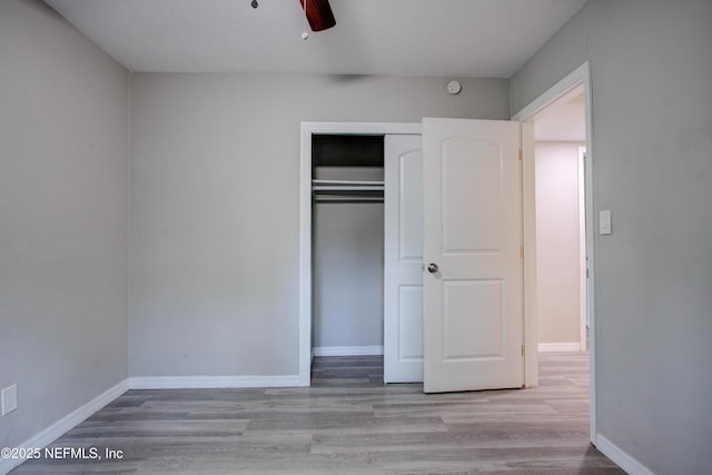 unfurnished bedroom with a closet, a ceiling fan, wood finished floors, and baseboards