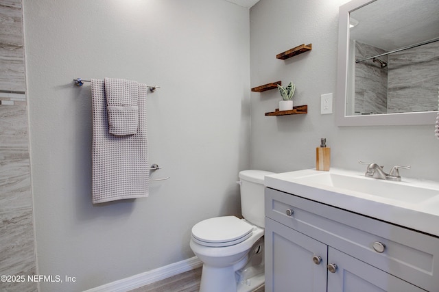 bathroom with vanity, toilet, a shower, baseboards, and wood finished floors