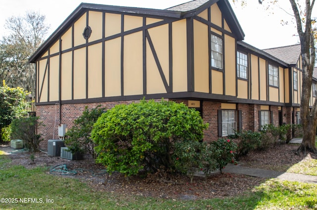view of side of home featuring brick siding and central air condition unit