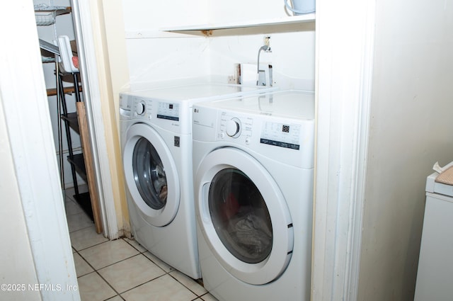 clothes washing area featuring light tile patterned floors, washer and dryer, and laundry area