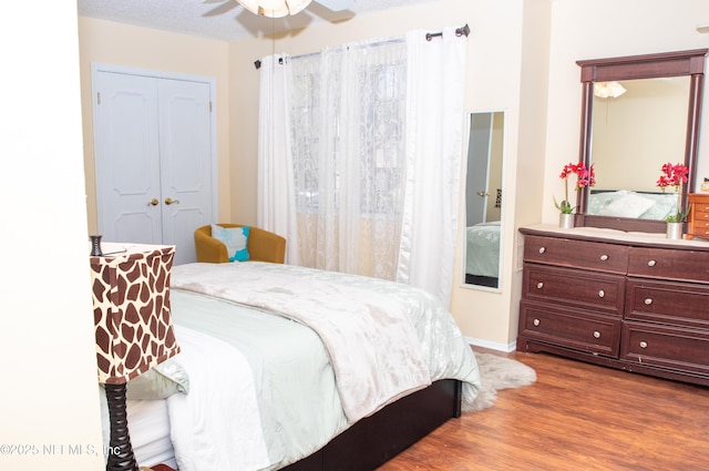 bedroom with baseboards, wood finished floors, ceiling fan, and a closet