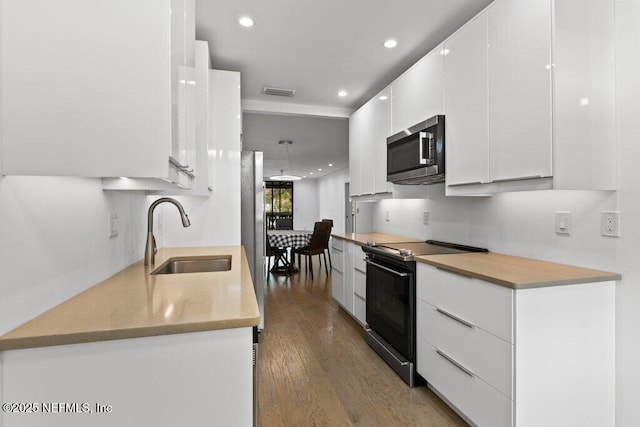 kitchen with white cabinets, appliances with stainless steel finishes, a sink, wood finished floors, and modern cabinets