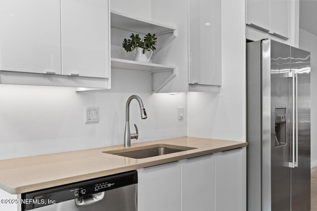 kitchen with a sink, light countertops, white cabinets, and stainless steel appliances