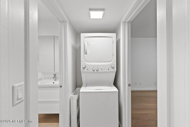 clothes washing area featuring laundry area, baseboards, and stacked washer / dryer