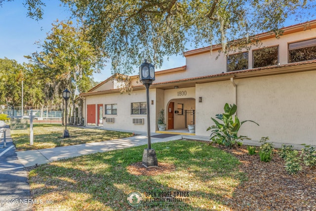 view of front of house with stucco siding, a front yard, and fence