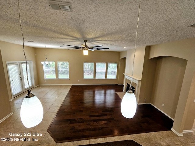unfurnished living room featuring a tile fireplace, tile patterned flooring, visible vents, arched walkways, and ceiling fan