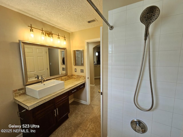 full bath with vanity, tile patterned floors, a textured ceiling, and tiled shower