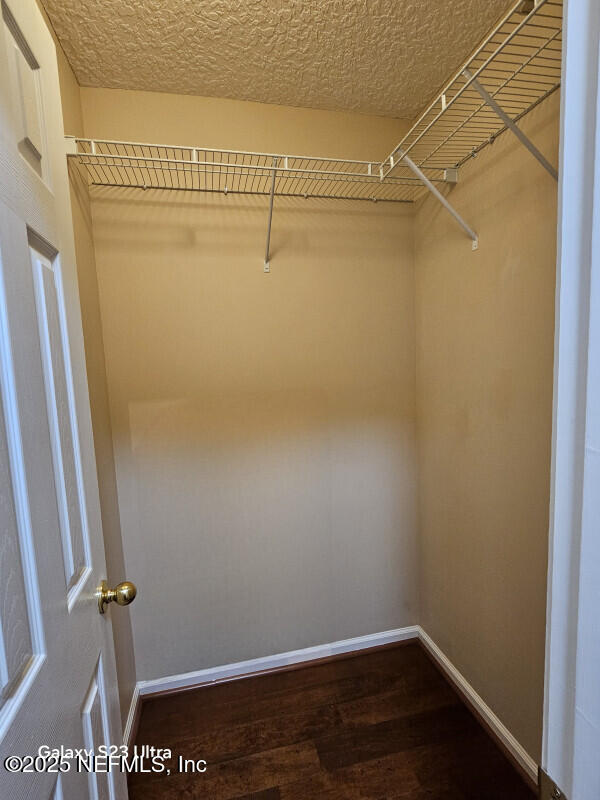 walk in closet with wood finished floors