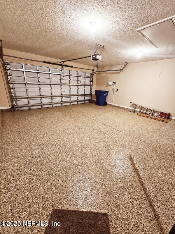garage with baseboards and a garage door opener