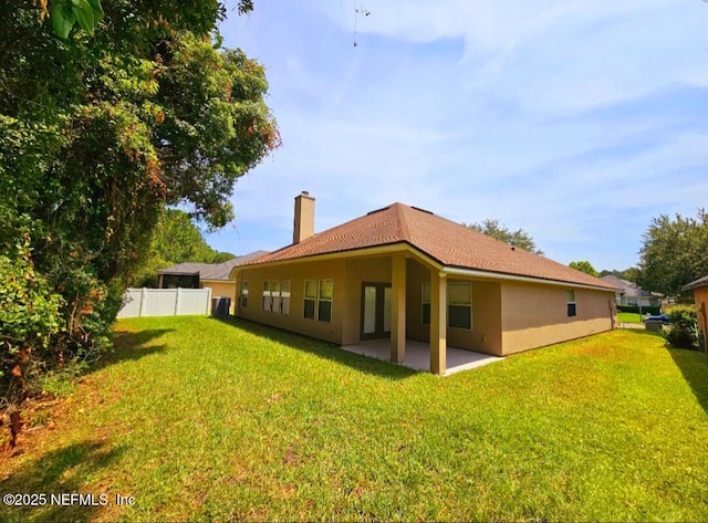 back of property featuring fence, a patio area, a chimney, and a yard