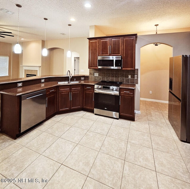 kitchen with tasteful backsplash, a sink, hanging light fixtures, arched walkways, and appliances with stainless steel finishes
