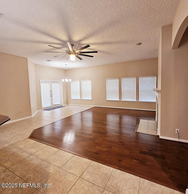 spare room with tile patterned flooring, a textured ceiling, and ceiling fan with notable chandelier