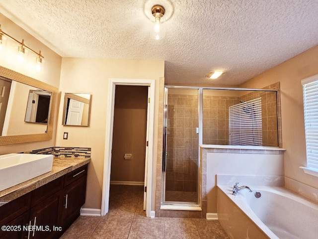bathroom with a textured ceiling, a stall shower, tile patterned flooring, a garden tub, and vanity