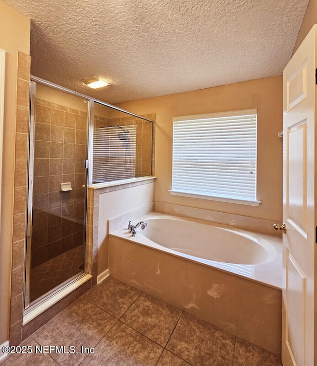 full bath with a bath, tile patterned floors, a textured ceiling, and a stall shower