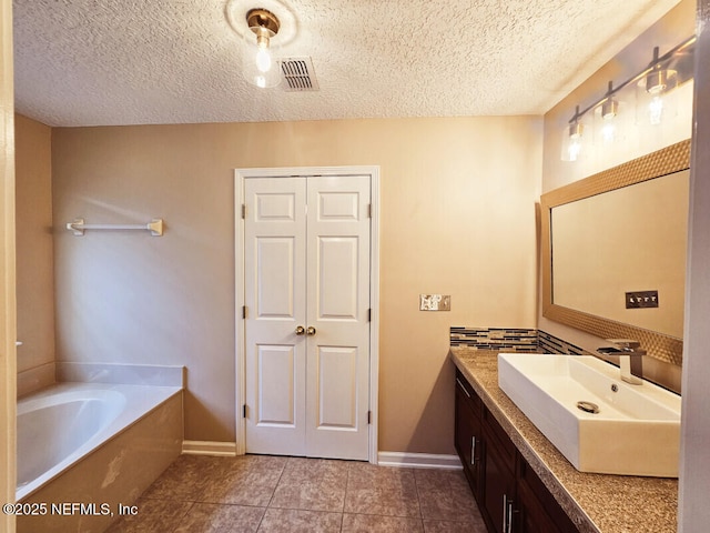 full bathroom with a textured ceiling, visible vents, tile patterned flooring, a garden tub, and vanity