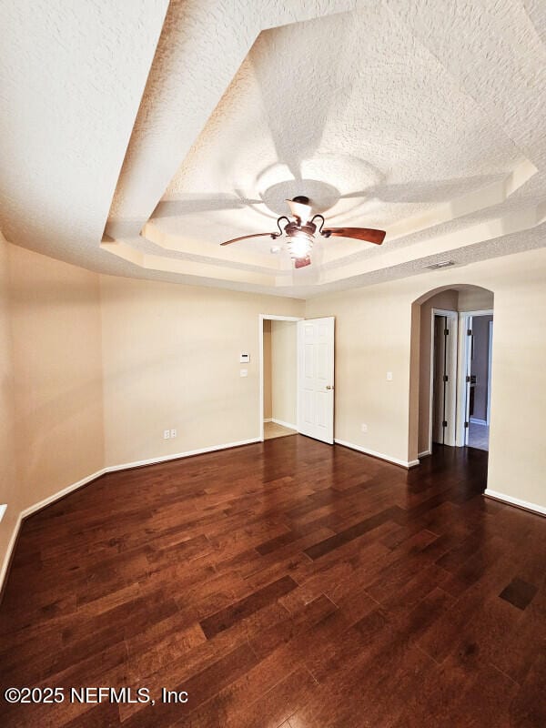 spare room featuring a ceiling fan, a tray ceiling, and a textured ceiling