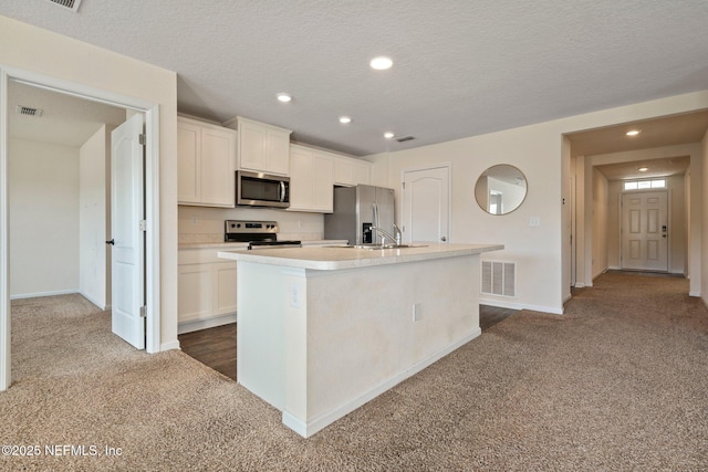 4402 Warm Springs Way, Middleburg, FL 32068 - kitchen with stainless steel appliances, dark colored carpet, a kitchen island with sink, white cabinets, and recessed lighting