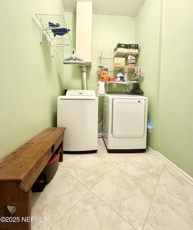 9421 Osprey Branch Trl Unit 4, Jacksonville, FL 32257 - laundry area featuring washing machine and dryer, light tile patterned flooring, laundry area, baseboards, and a textured ceiling