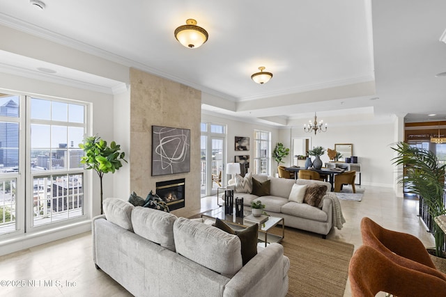 living room with an inviting chandelier, crown molding, a fireplace, and a wealth of natural light