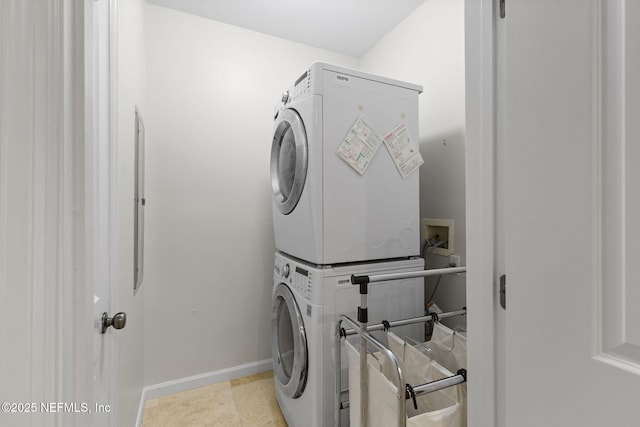 laundry area with laundry area, stacked washer and dryer, and baseboards
