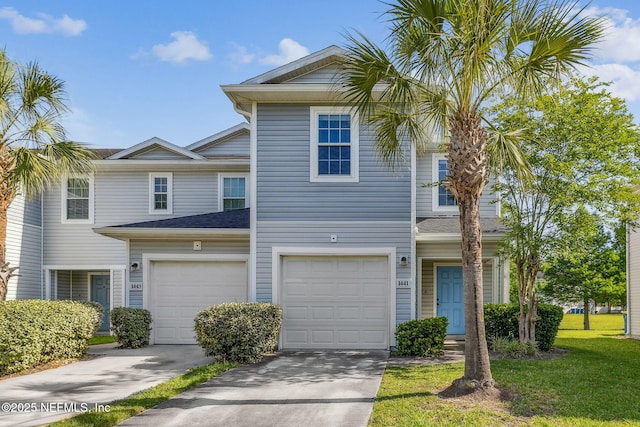view of property with a front yard, concrete driveway, and an attached garage