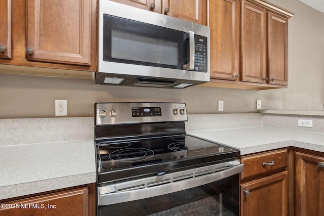kitchen featuring brown cabinets, stainless steel appliances, and light countertops