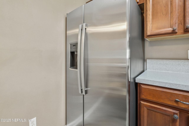 interior details featuring light countertops, brown cabinets, and stainless steel fridge with ice dispenser