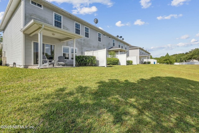 rear view of house featuring fence, a yard, and a patio area