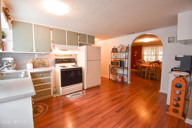 kitchen featuring a sink, wood finished floors, white appliances, and arched walkways