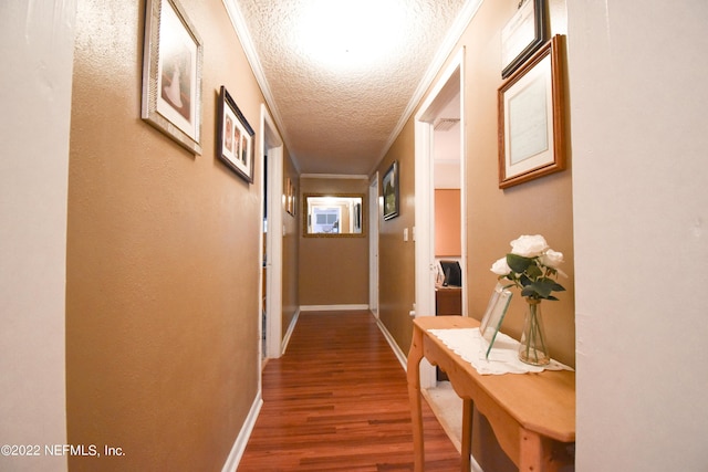 corridor featuring a textured ceiling, wood finished floors, and baseboards