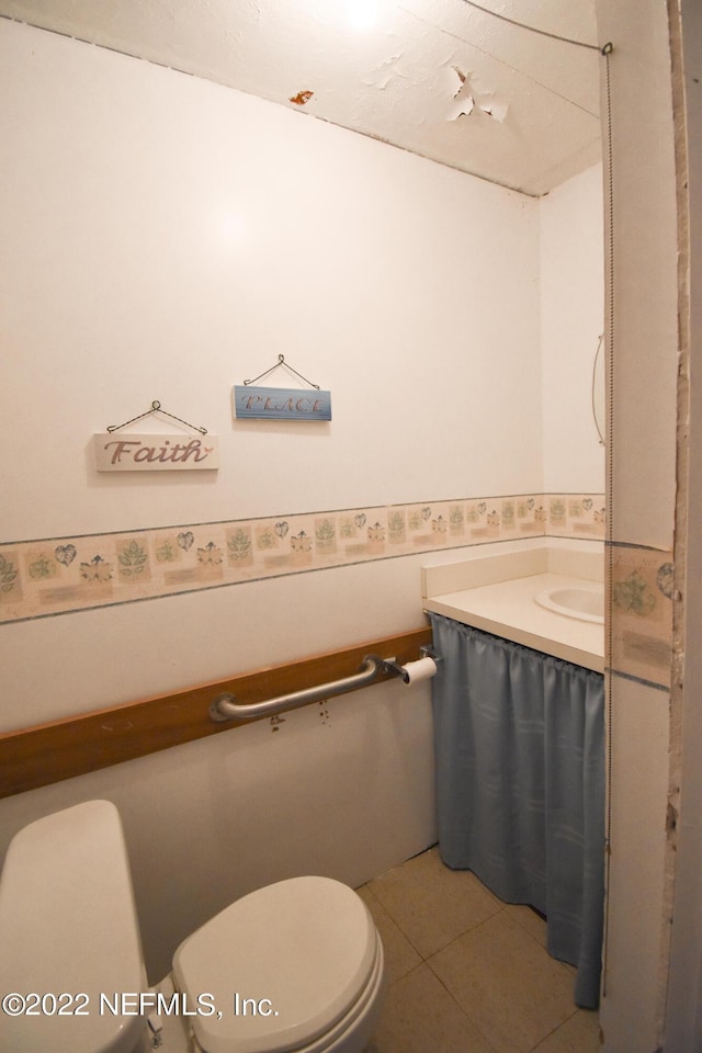 bathroom with toilet, vanity, and tile patterned floors