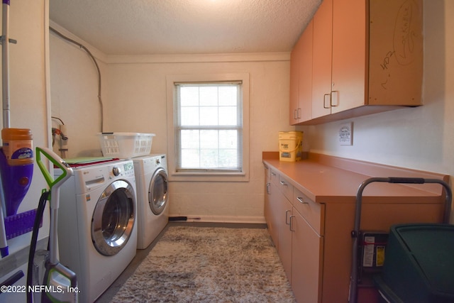 washroom with a textured ceiling, cabinet space, and washing machine and dryer