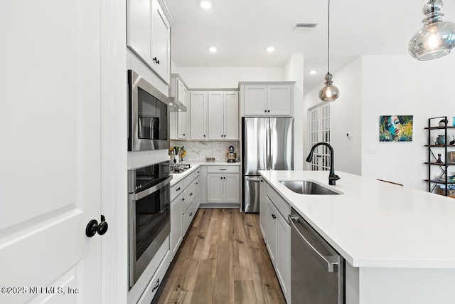 kitchen featuring visible vents, light countertops, a sink, light wood-style flooring, and appliances with stainless steel finishes
