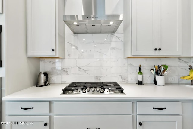 kitchen featuring light countertops, stainless steel gas cooktop, backsplash, and wall chimney range hood