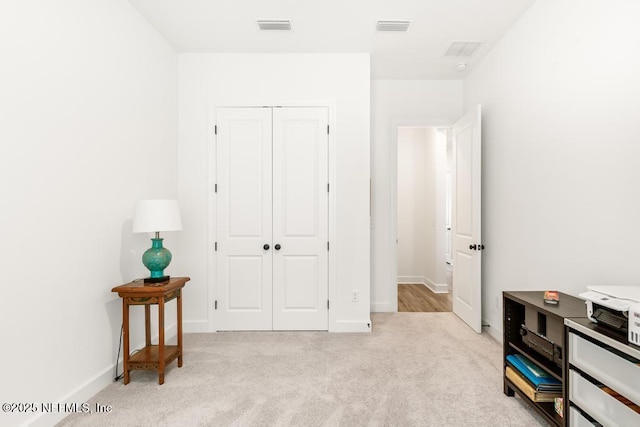 bedroom featuring baseboards, light carpet, a closet, and visible vents