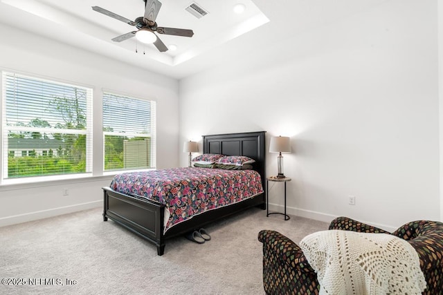 carpeted bedroom featuring a ceiling fan, baseboards, visible vents, and a raised ceiling