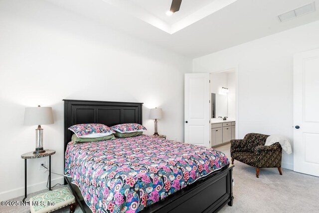 bedroom with visible vents, a ceiling fan, ensuite bath, and light colored carpet