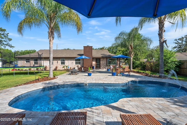 view of swimming pool featuring a trampoline, a fenced backyard, a yard, a fenced in pool, and a patio