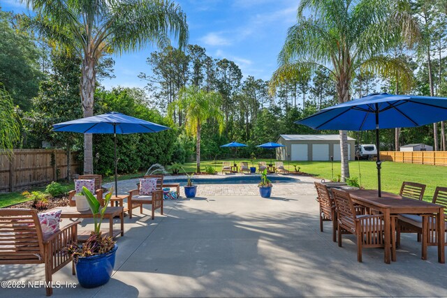 view of patio / terrace featuring a fenced backyard, an outbuilding, a fenced in pool, outdoor dining space, and a shed